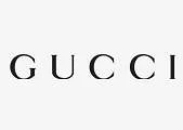Paveikslėlyje pavaizduotas žodis GUCCI juodomis didžiosiomis raidėmis dideliais tarpais vienspalviame baltame fone. Tai prabangių drabužių prekės ženklo "Gucci" logotipas.